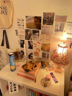 a white desk topped with lots of pictures and other items next to a lamp on top of a table