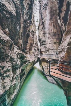 a narrow river in the middle of a canyon with blue water running between two large rocks