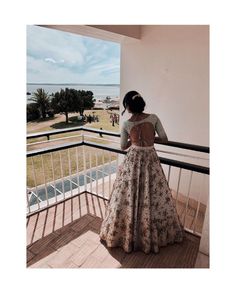 a woman standing on a balcony looking out at the ocean