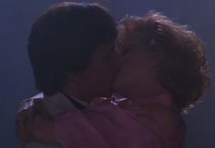 two people kissing each other in front of a blue background with light coming from behind them