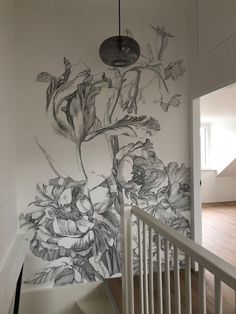 a wall with flowers painted on it next to a stair case and light fixture hanging from the ceiling