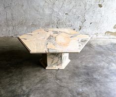 a marble table sitting on top of a cement floor