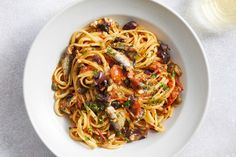 a white bowl filled with pasta and olives