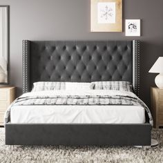 a bed with a black headboard sitting on top of a white carpeted floor