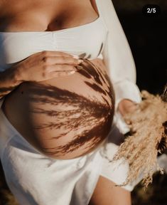 a pregnant woman with her hands on her belly and grass in front of her stomach