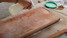 a person is pouring something into a container on top of a piece of plywood