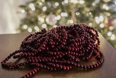 a bunch of beads sitting on top of a wooden table next to a christmas tree