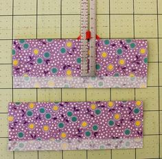 two pieces of purple fabric with yellow and green flowers on them next to a ruler