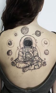 an astronaut tattoo on the back of a woman's upper arm and shoulder, with planets around her