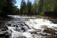 a river running through a forest filled with lots of rocks and water surrounded by trees