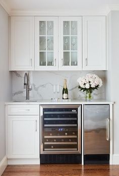 a kitchen with white cabinets and stainless steel appliances, including a wine cooler in the center