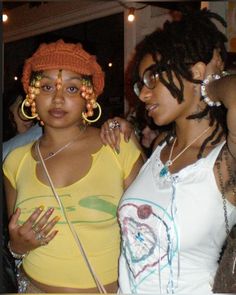 two women standing next to each other with large hoop earrings on their head and one wearing a yellow shirt