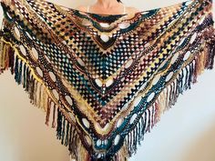 a woman wearing a multicolored crocheted shawl with tassels