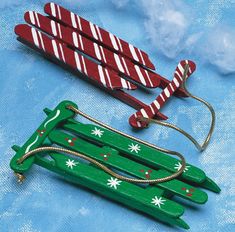 two wooden sleds with snowflakes and candy canes on them sitting on a blue background