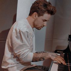 a man with tattoos playing the piano