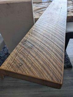 a wooden bench sitting on top of a hard wood floor next to a white chair