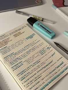 a notepad with writing on it next to a pen and a laptop computer sitting on a desk