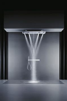 a shower head in the middle of a room with light coming from it's ceiling