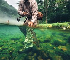 a man standing in the water while holding a fishing rod and fish hook with his right hand