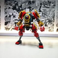 a lego robot standing in front of a comic book wall with an action figure next to it