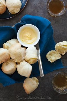 rolls and butter on a blue cloth next to two bowls with dipping sauce in them