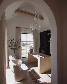 an archway leading to a living room with two chairs and a desk in the middle