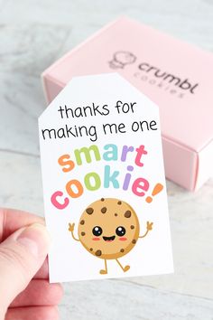 a hand holding up a small cookie gift tag that says thanks for making me one smart cookie