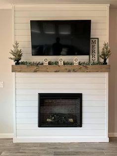 a fireplace with a flat screen tv mounted above it and greenery on the mantel