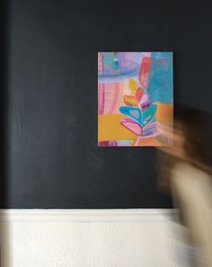 a blurry image of a person walking in front of a painting on the wall