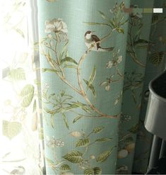 a bird sitting on top of a green curtain next to a potted plant in front of a window