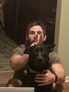 a man sitting on the floor with his dog in front of him and holding it up to his face