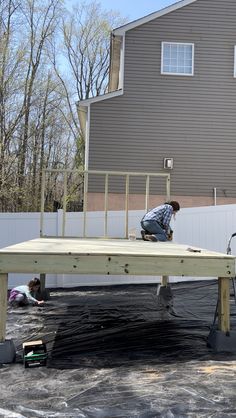 two men working on a wooden structure in front of a house