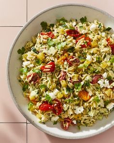 a white bowl filled with lots of food on top of a pink tile countertop