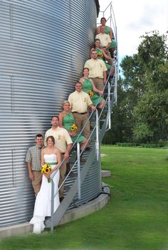 a group of people that are standing in front of a silo with sunflowers