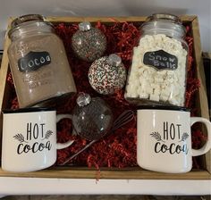 three coffee mugs filled with hot cocoa and marshmallows in a wooden box