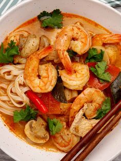 a white bowl filled with noodles and shrimp next to chopsticks on top of a table