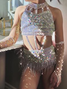 a woman in a silver outfit standing next to a counter with her hands on her hips