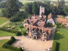 an aerial view of a large brick building in the middle of a lush green field