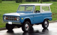 an old ford bronco is parked in the rain