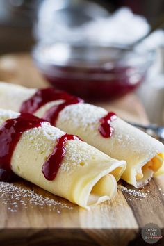 two crepes covered in powdered sugar and ketchup on a cutting board