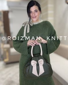 a woman is holding a green and white purse