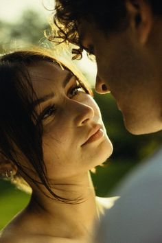 a young man and woman are looking at each other while the sun shines on them