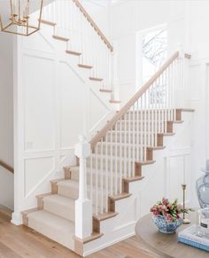 there is a white staircase in the living room with flowers on the table next to it