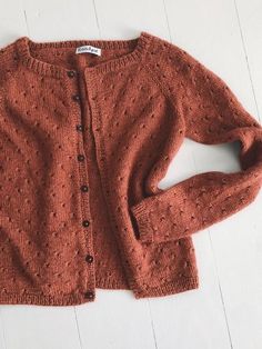 an orange cardigan sweater sitting on top of a white table