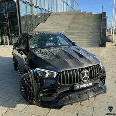 a black mercedes benz amg coupe parked in front of a building with stairs and steps