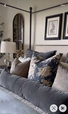 a bed with many pillows on it and pictures above the headboard in a bedroom