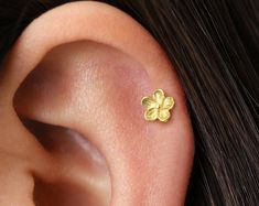 a close up of a person's ear with a small flower on the side