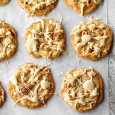 twelve cookies with white icing and nuts on a sheet of parchment paper, ready to be eaten