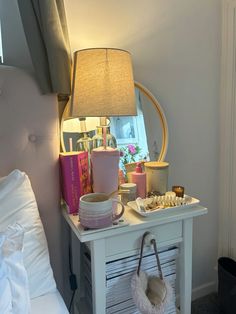 a white table topped with a lamp next to a mirror and other items on top of it