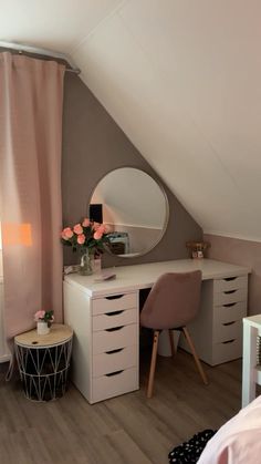 a bedroom with a desk, mirror and dresser in it's corner area next to a window